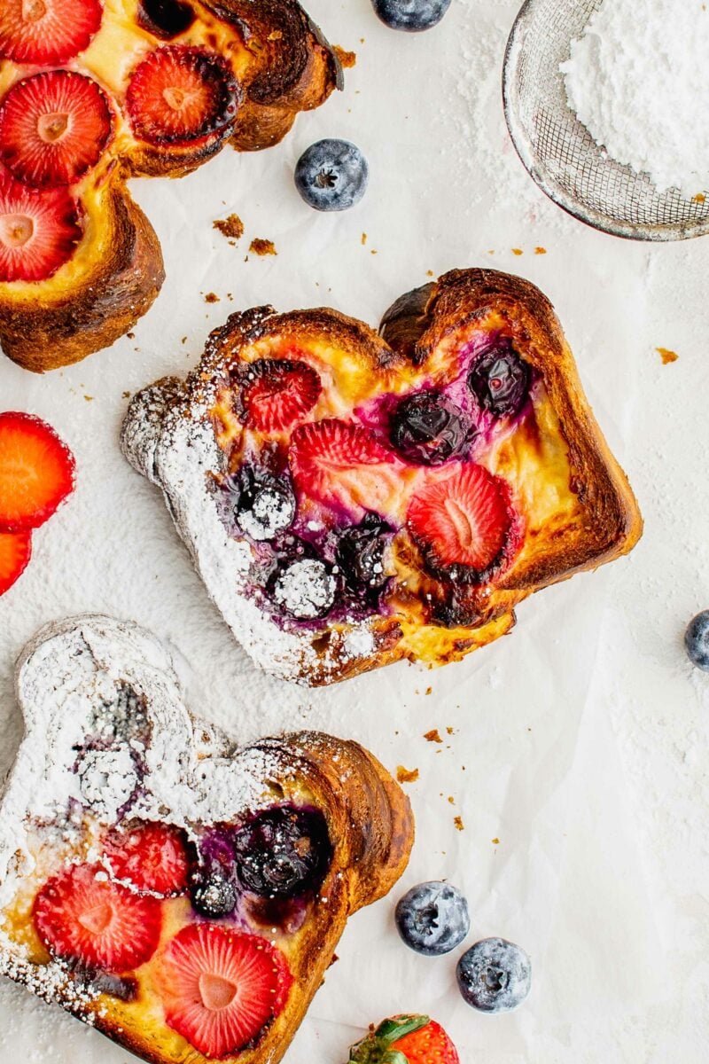 A few slices of custard toast are dusted with powdered sugar and presented on a white surface.