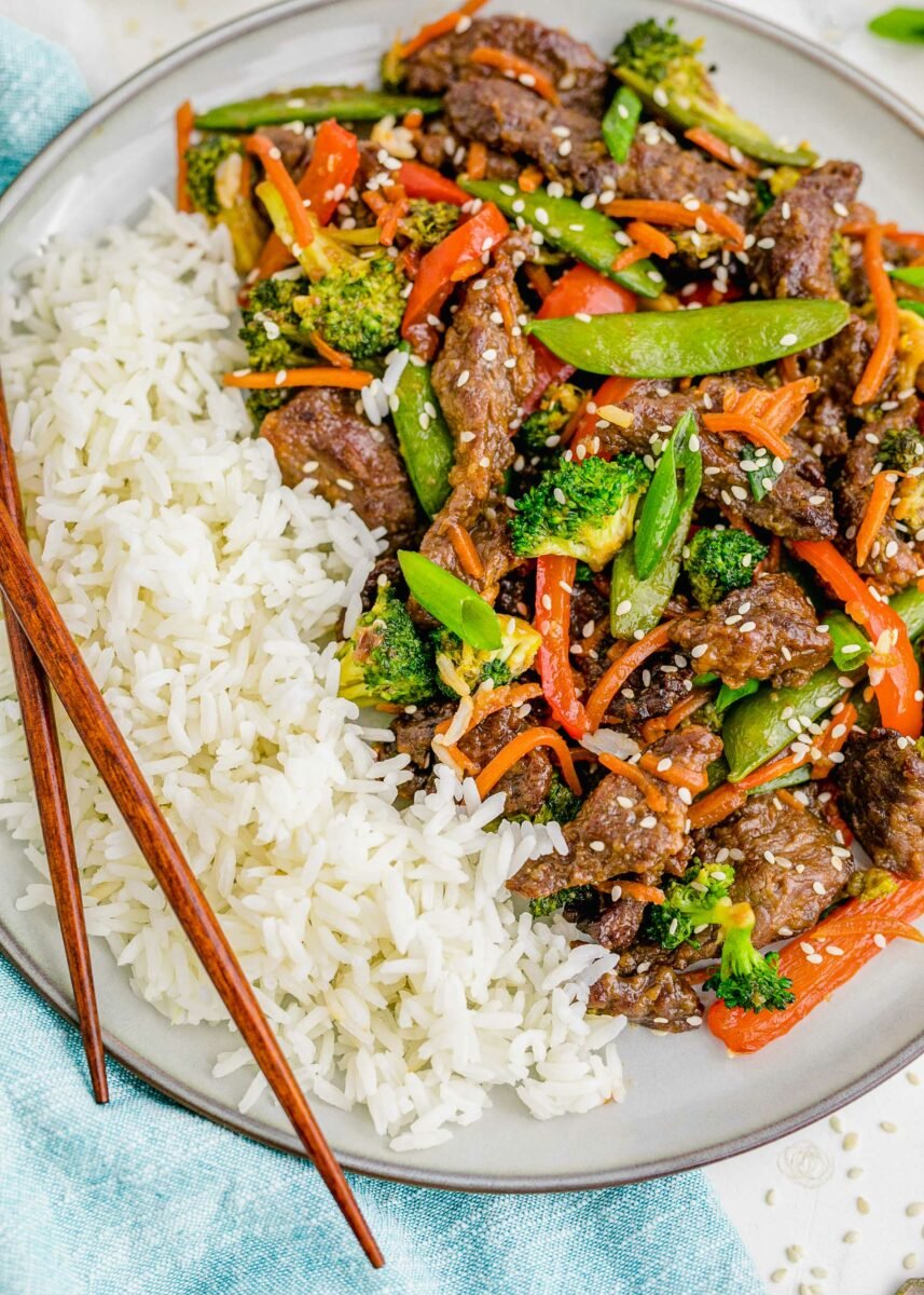 Rice and beef stir fry is presented with chopsticks. 