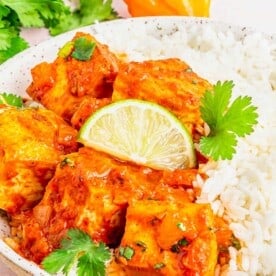 Coconut Caribbean Tofu in bowl with white rice, garnished with lime wedge and cilantro