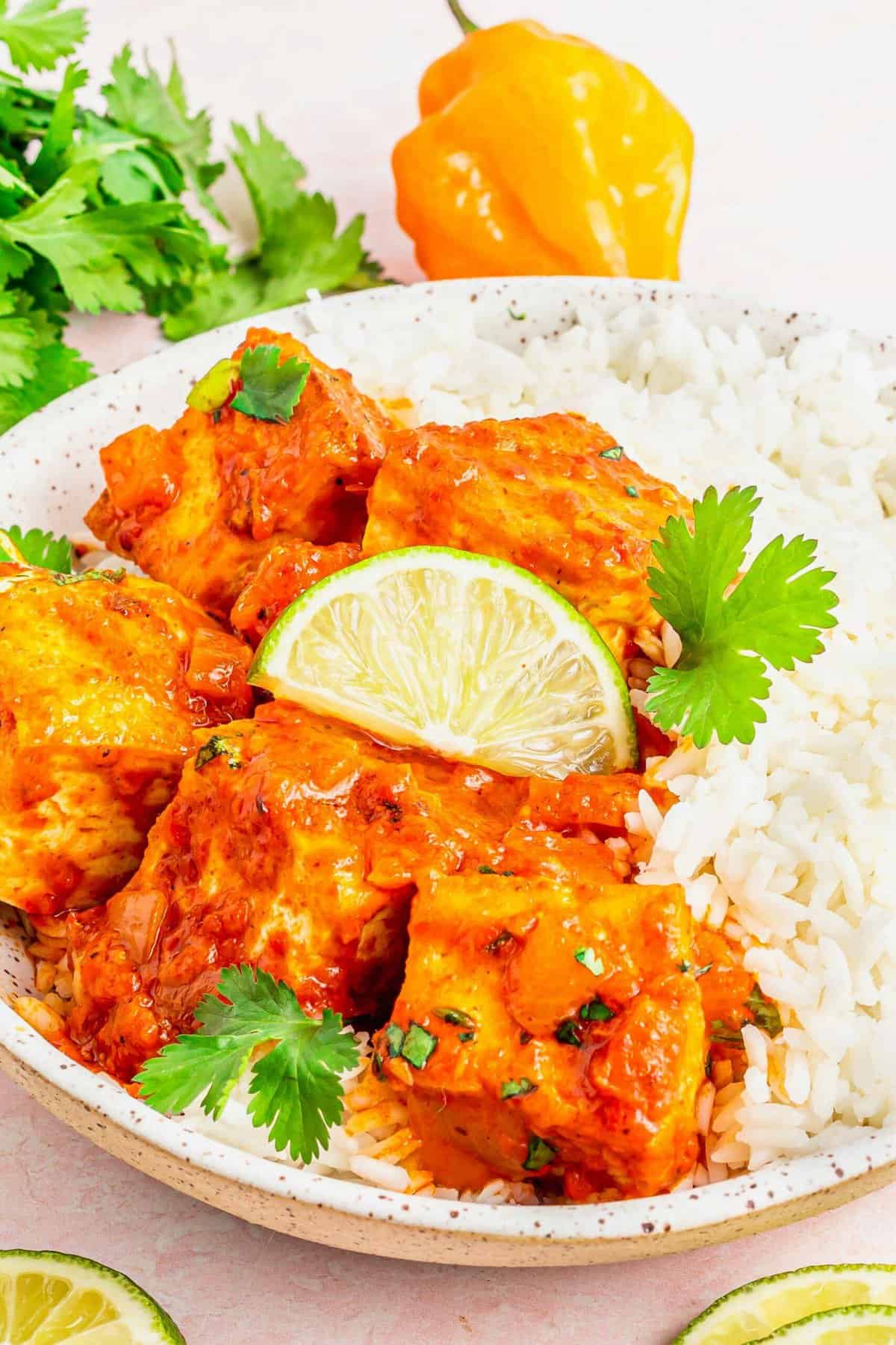 Coconut Caribbean Tofu in bowl with white rice, garnished with lime wedge and cilantro