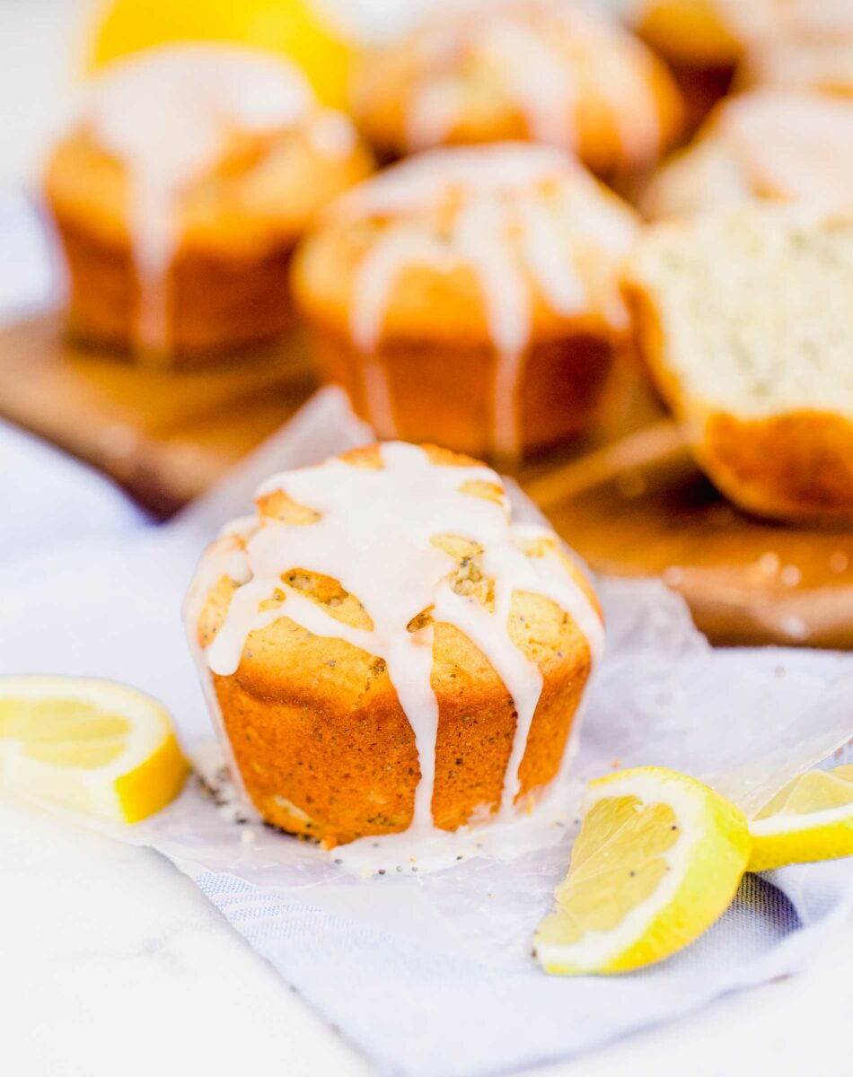 A glazed muffin is placed on a tea towel next to lemon slices. 