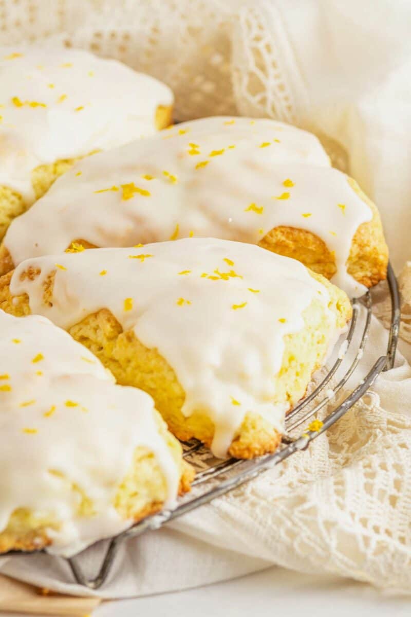 Glazed scones on a wire cooling rack are garnished with orange zest.