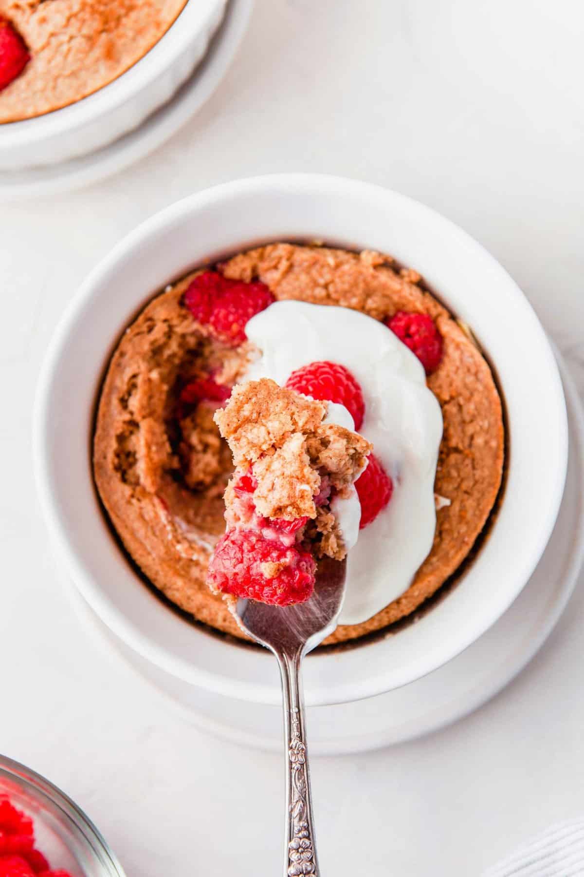 Overhead view of raspberry baked oatmeal in white bowl with spoon