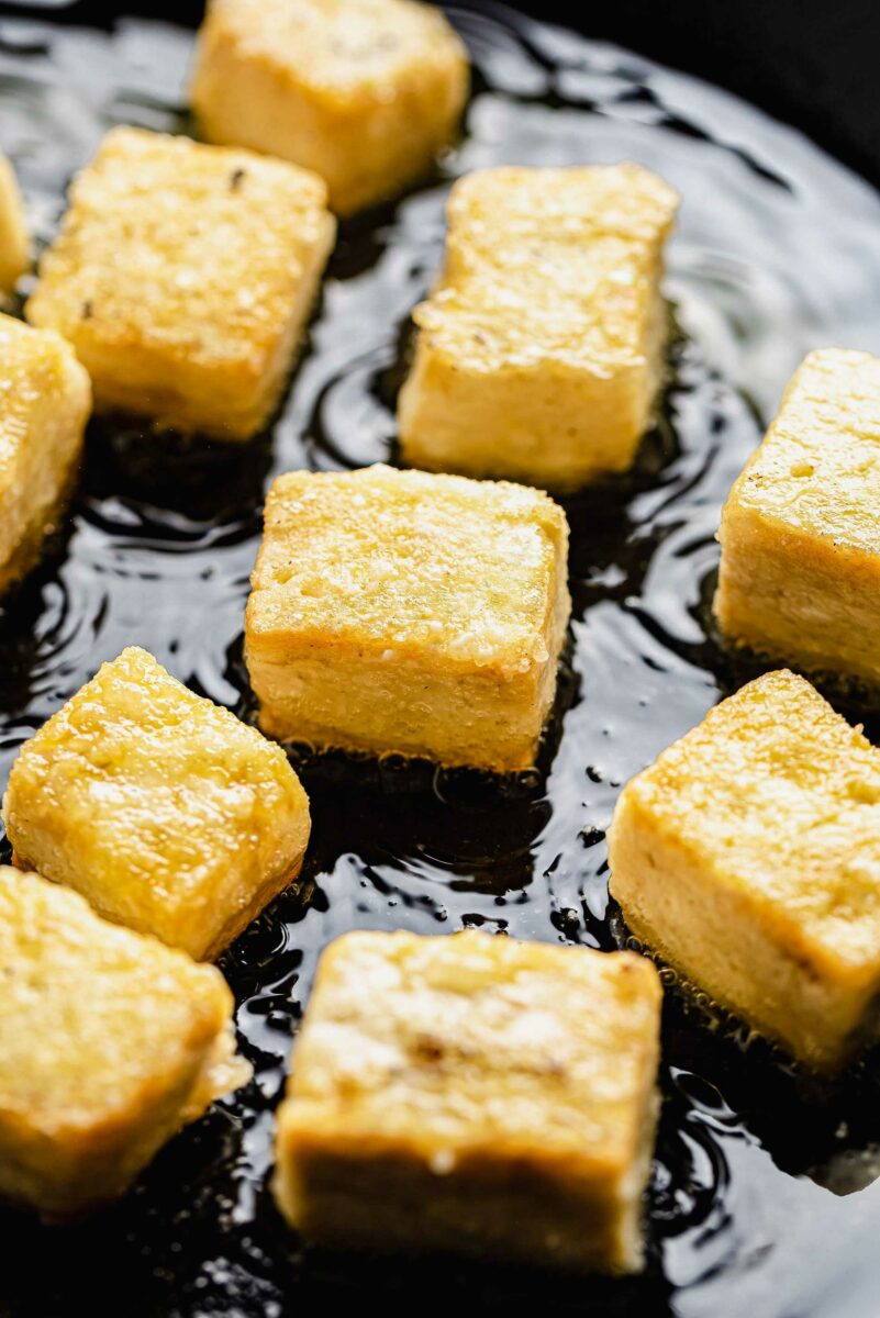 Close up of cubes of tofu frying in a pan