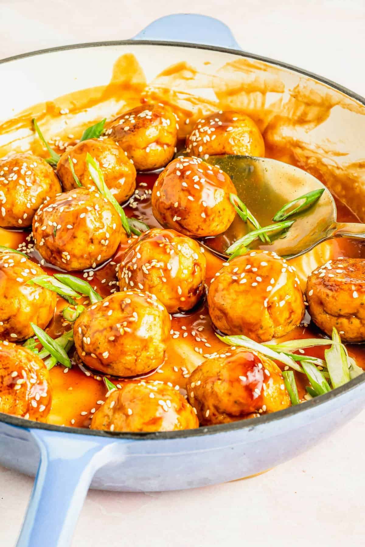 Teriyaki tofu meatballs in enamel skillet with scallions and sesame seeds