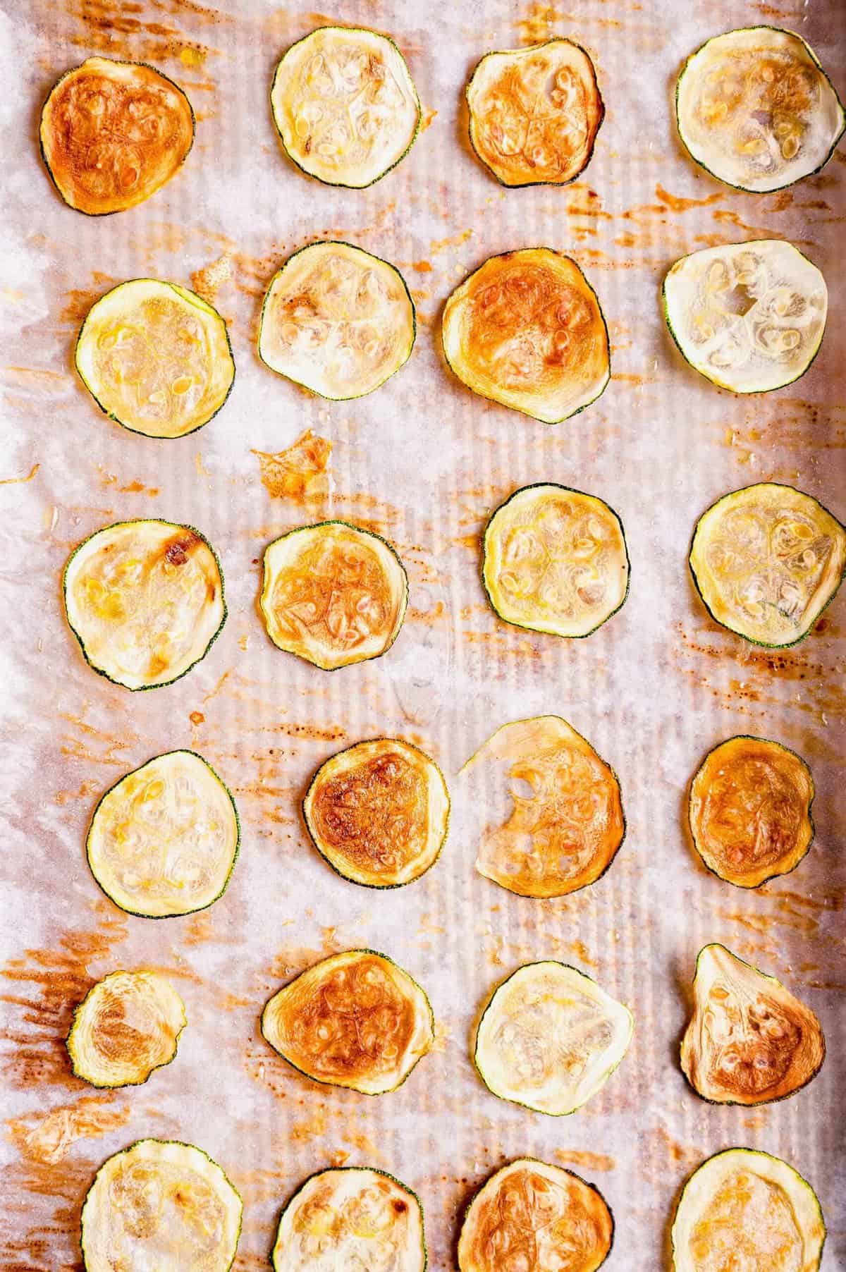 Overhead view of zucchini chips on parchment-lined baking sheet