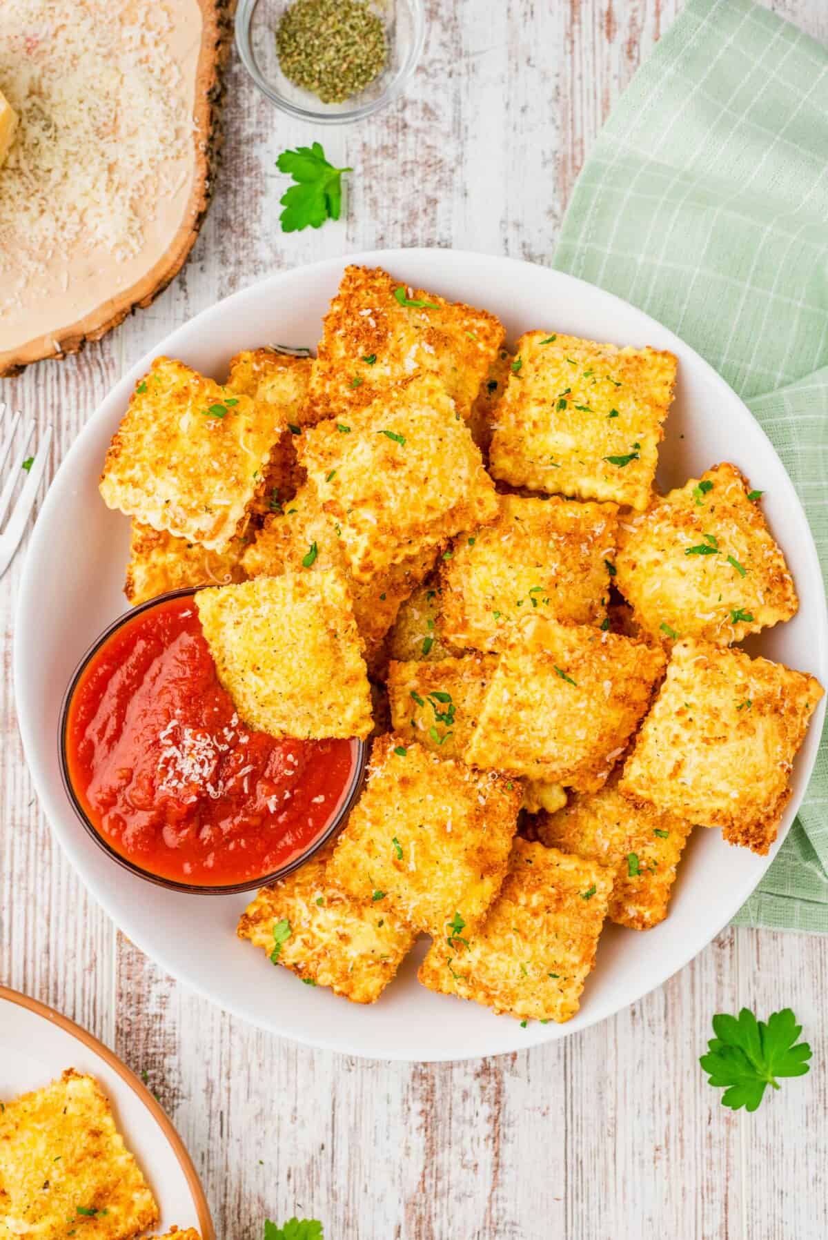 Overhead view of crispy ravioli in bowl with marinara