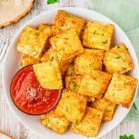 Overhead view of crispy ravioli in bowl with marinara