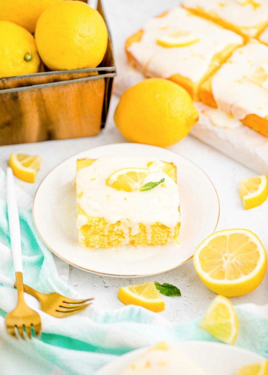 A garnished piece of lemon sheet cake is placed on a small round white plate. 