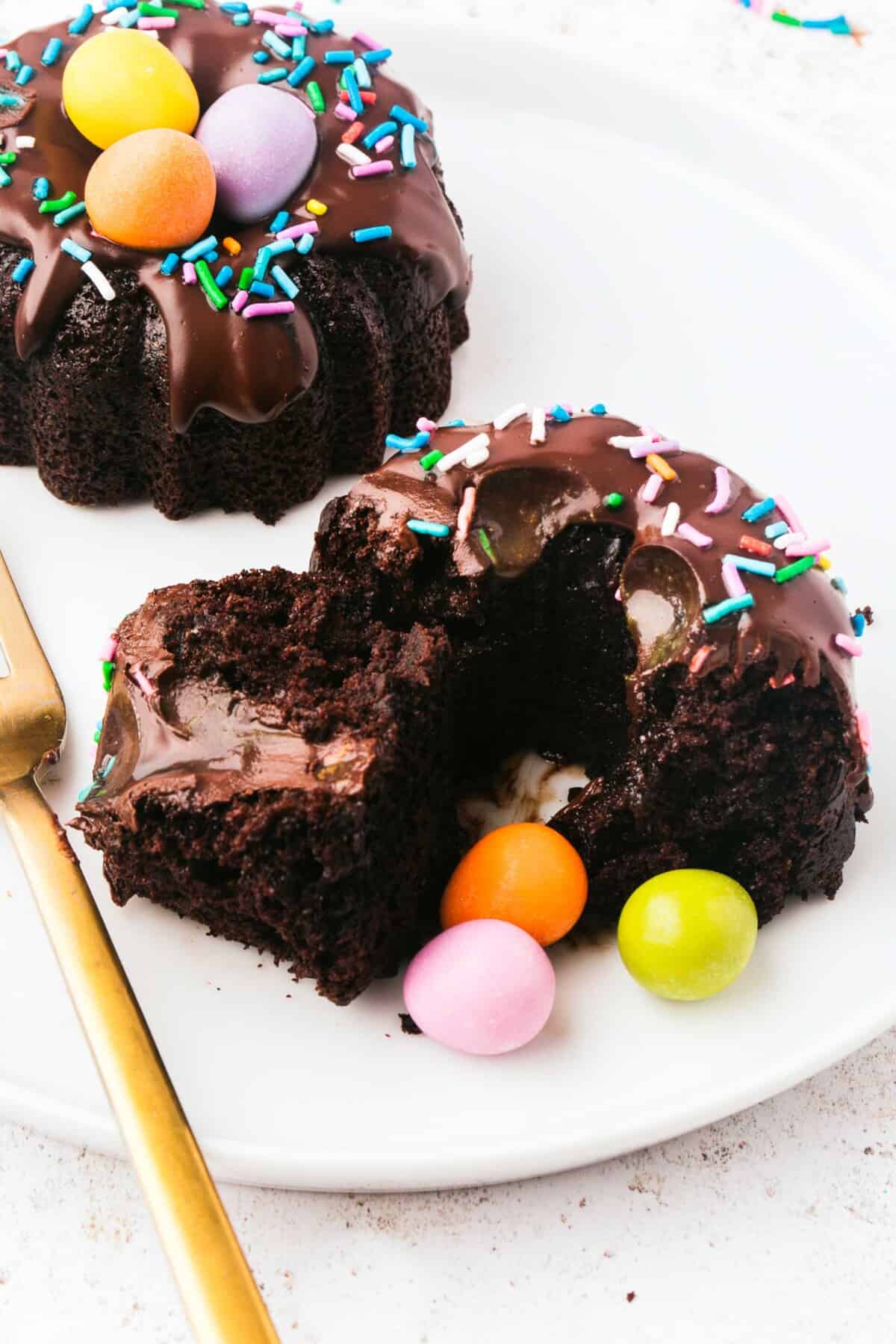 A bundt cake has been cut in half, revealing chocolate ganache that has drizzled through the center of the cake.