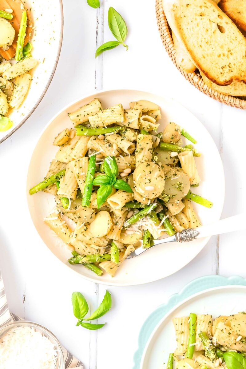 A white plate is topped with green beans, pasta, and potatoes, all tossed in pesto.