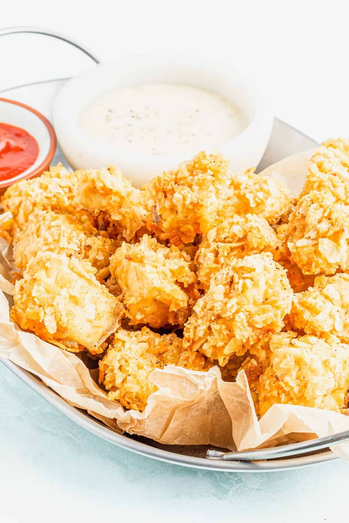 Basket of popcorn tofu with 2 bowls of dipping sauce