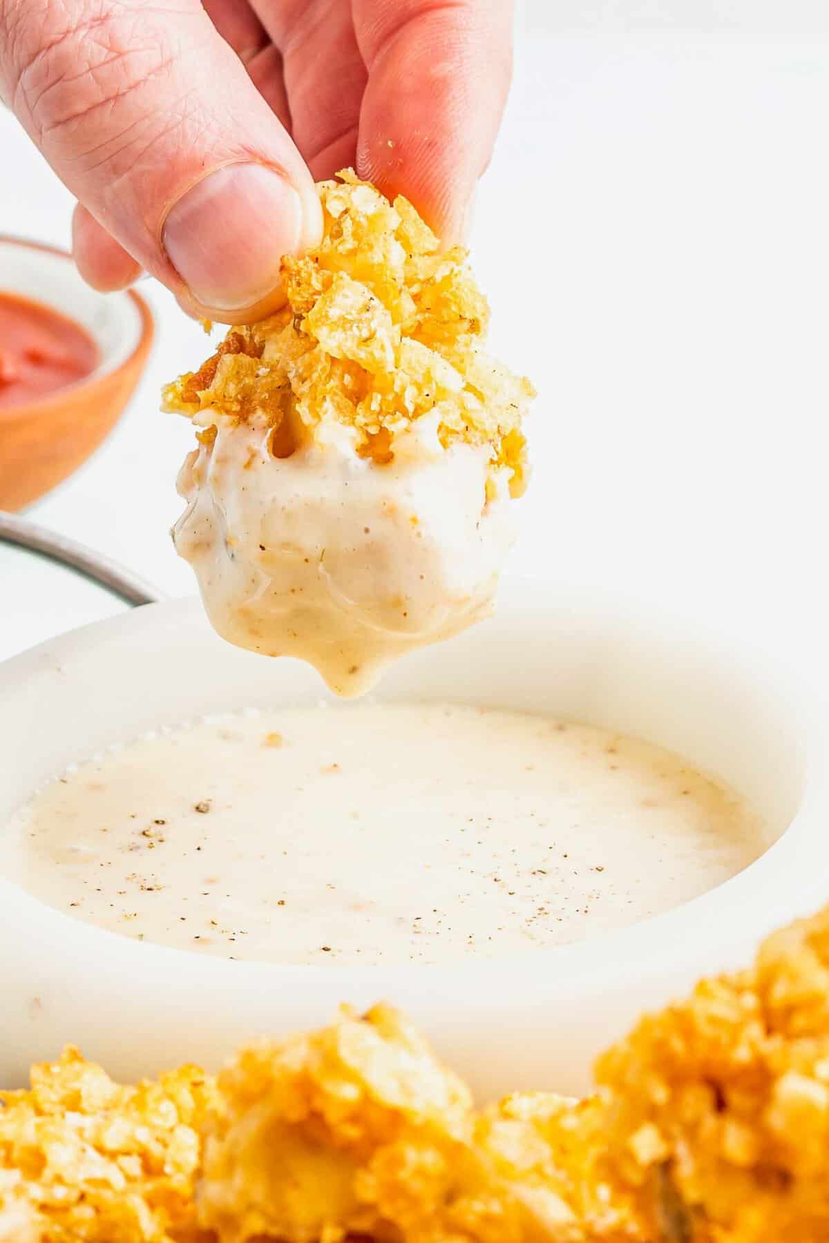 Dipping popcorn chicken into creamy sauce