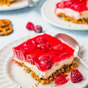 Square of raspberry pretzel salad on plate with spoon