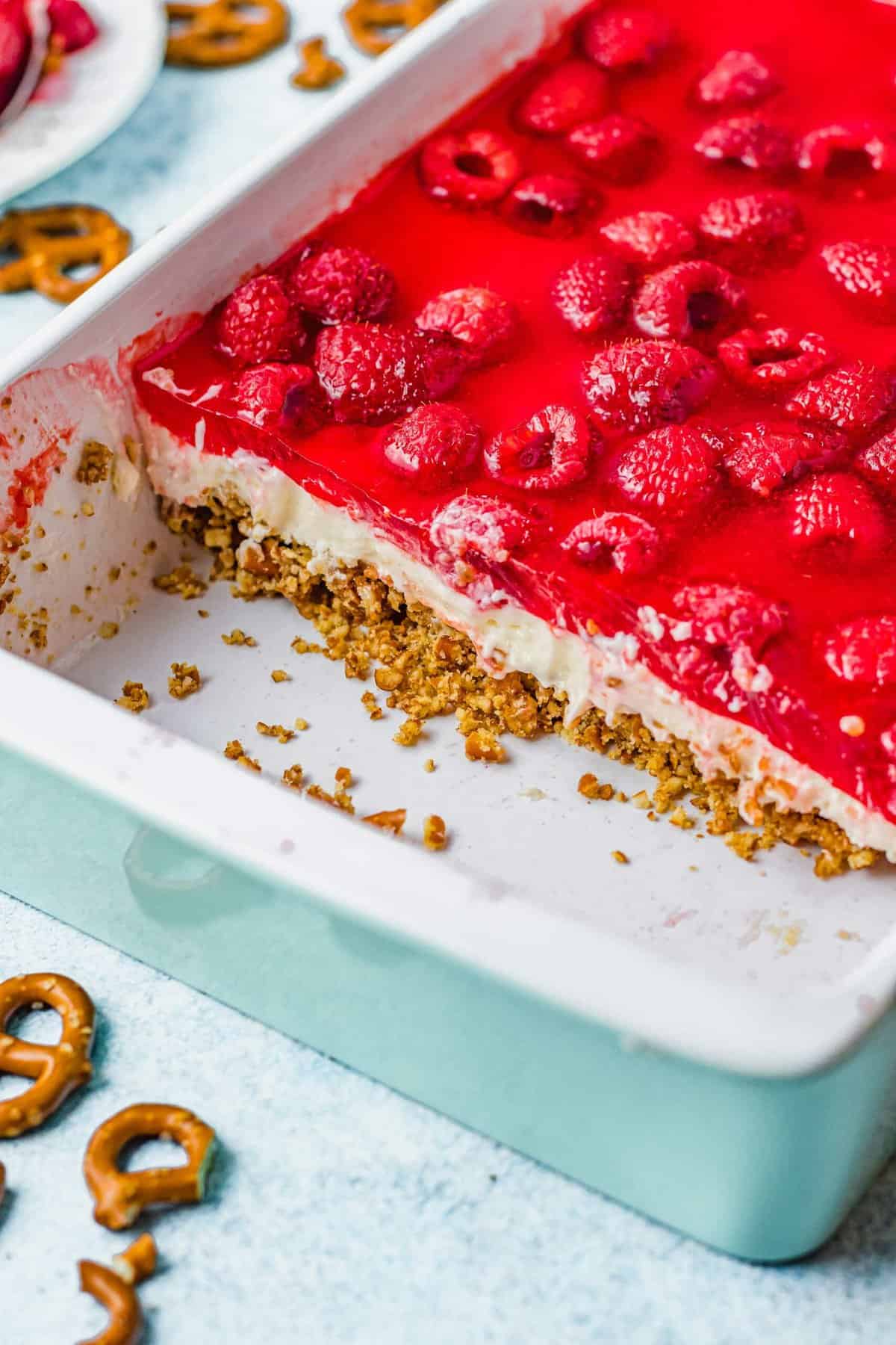 Raspberry pretzel salad in dish, with row of slices removed to show layers