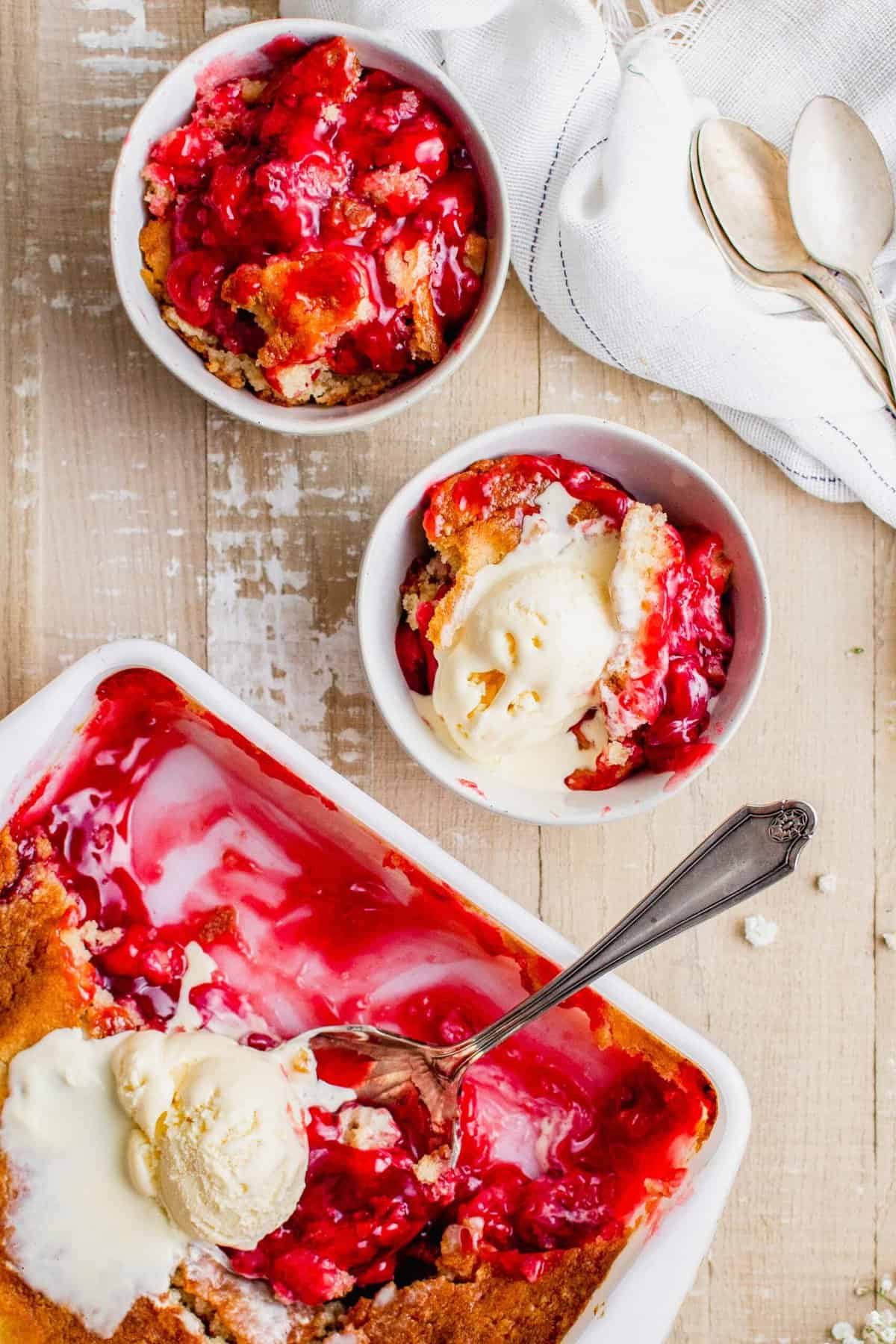 Overhead view of cherry cobbler in 2 bowls and baking dish