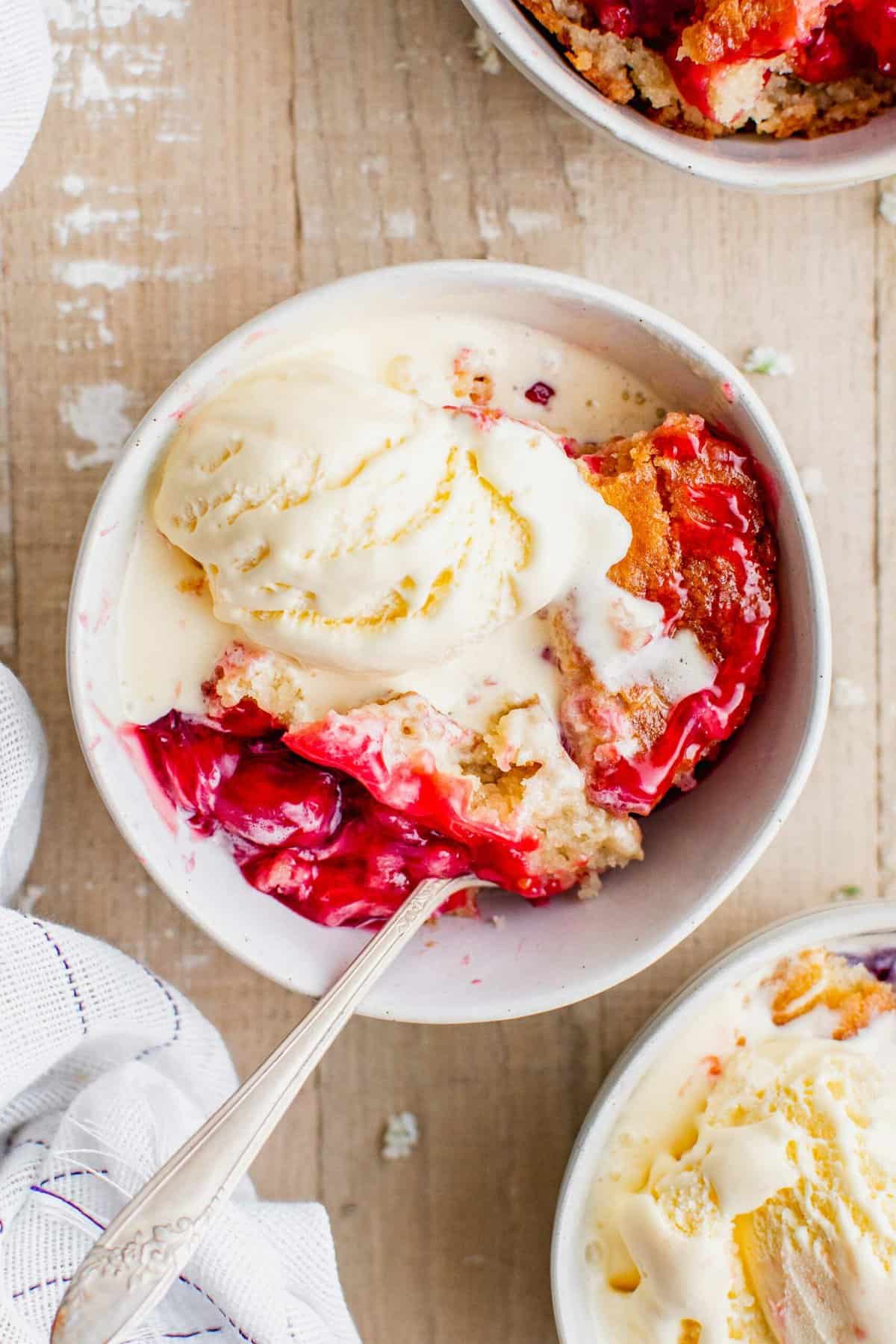 Overhead view of cherry cobbler in bowl with ice cream