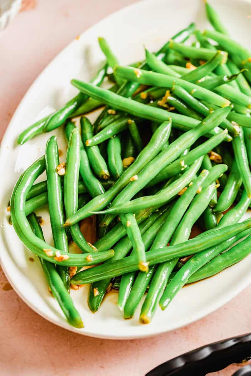 A white plate is topped with a large serving of marinated garlic and soy green beans. 