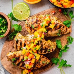 Grilled mojo chicken on cutting board, topped with salsa