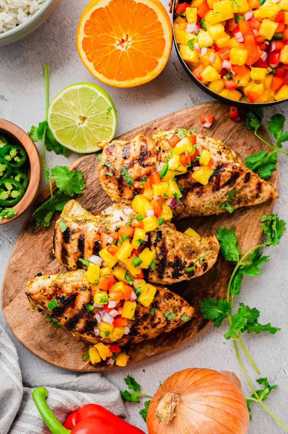 Grilled mojo chicken on cutting board, topped with salsa