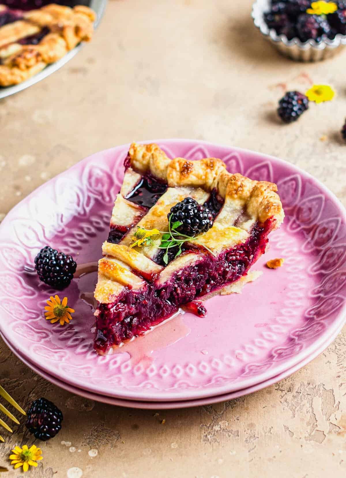 Slice of blackberry pie with lattice crust on purple plate