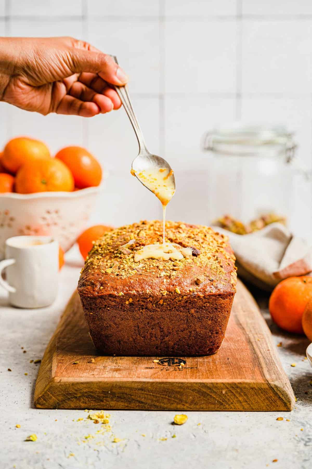 Drizzling glaze onto orange pistachio bread loaf