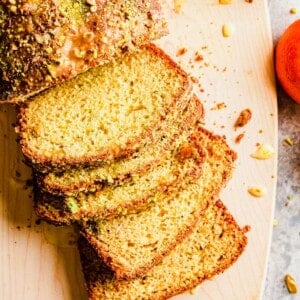 Sliced orange pistachio bread on cutting board