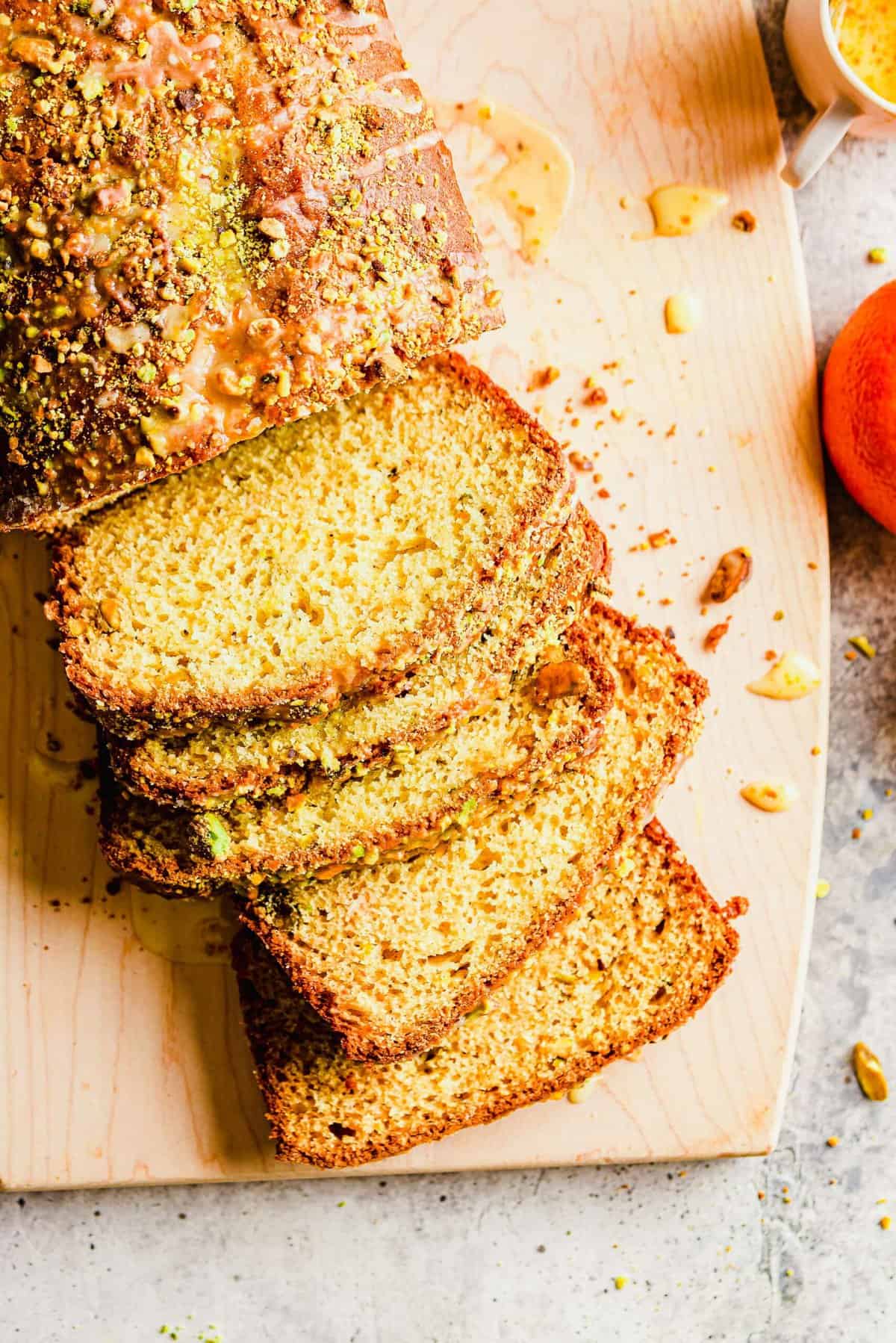 Sliced orange pistachio bread on cutting board