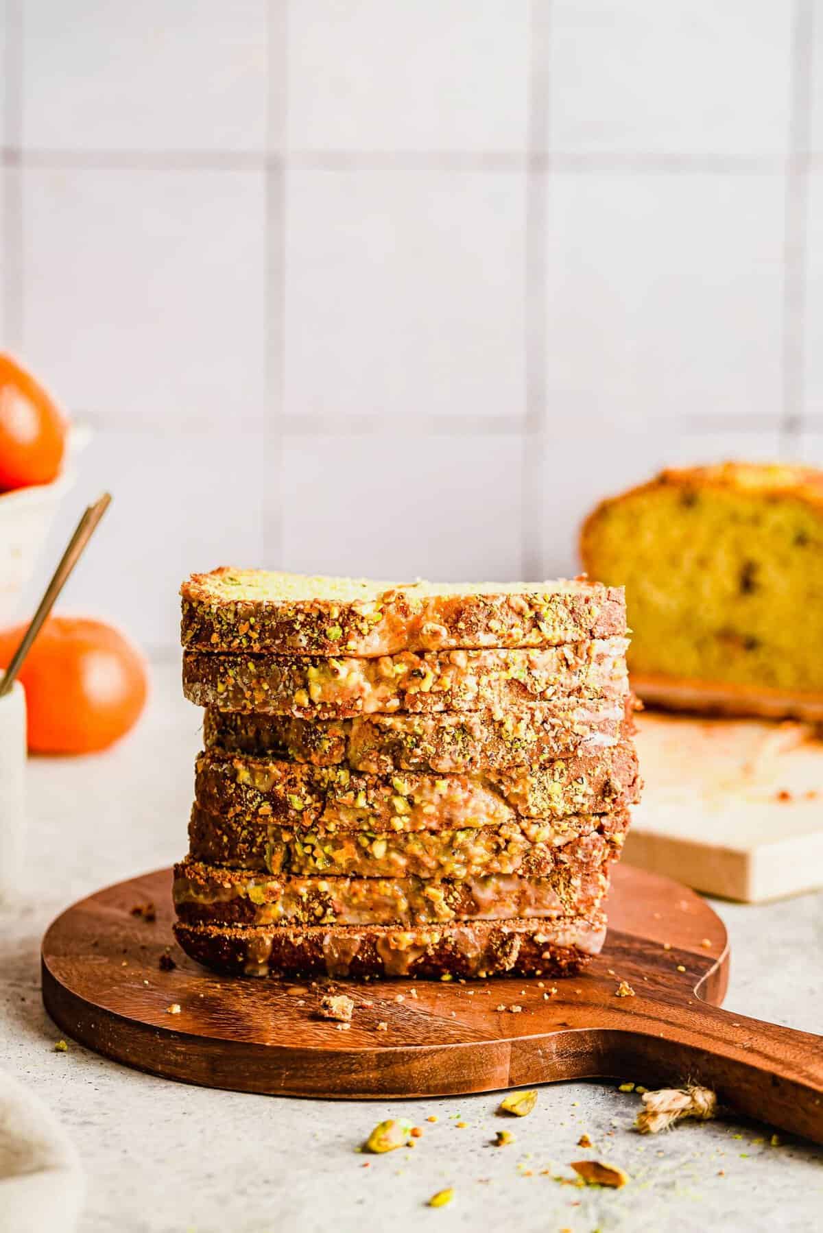 Stack of sliced orange pistachio bread on wood cutting board