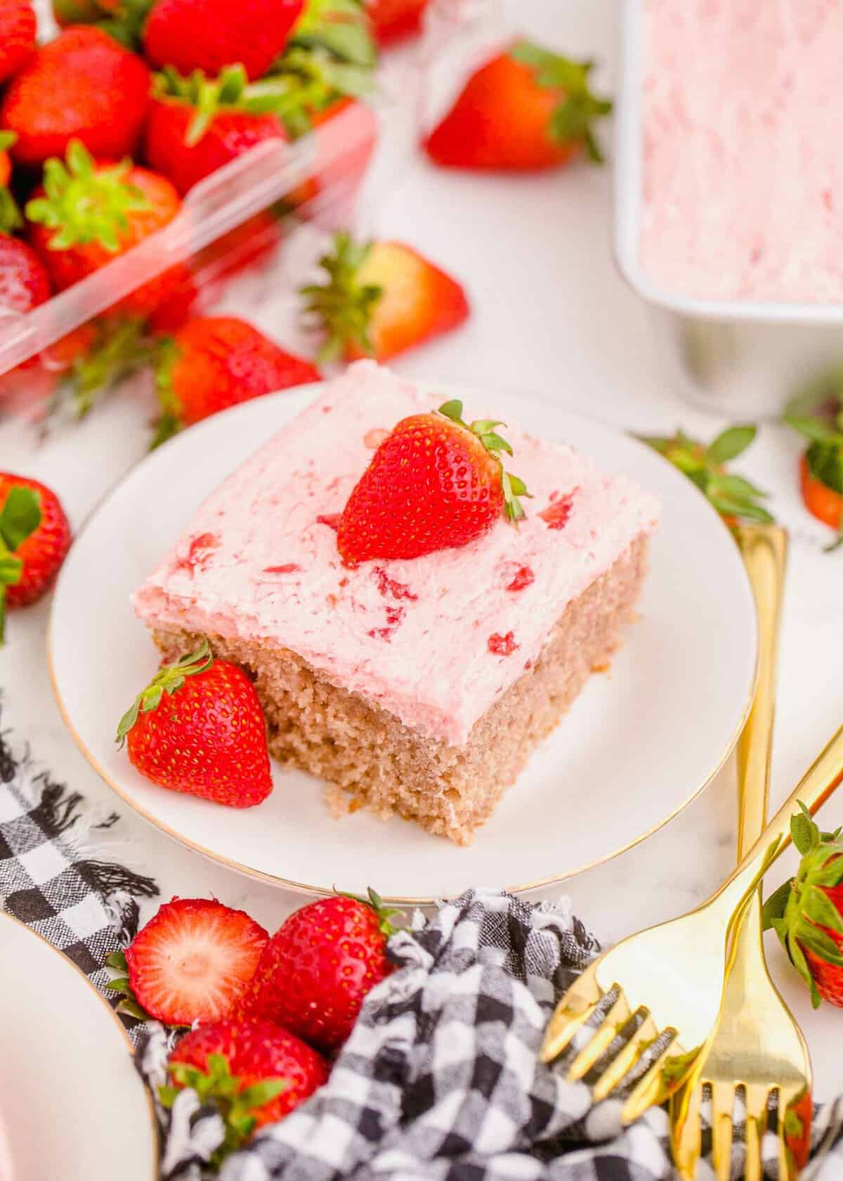 Strawberry sheet cake on plate, garnished with and surrounded by fresh strawberries