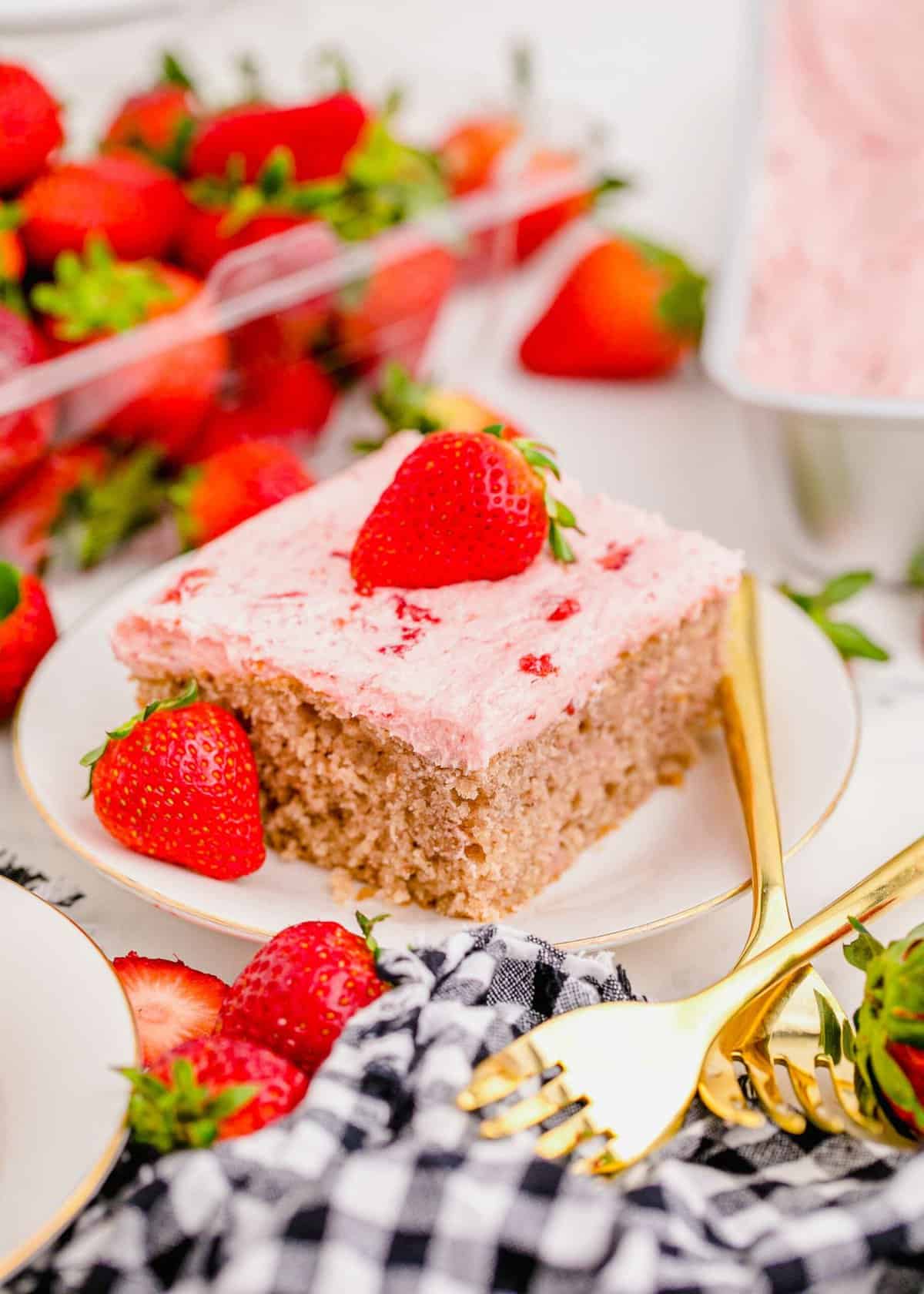 Strawberry sheet cake square on plate, garnished with fresh strawberries