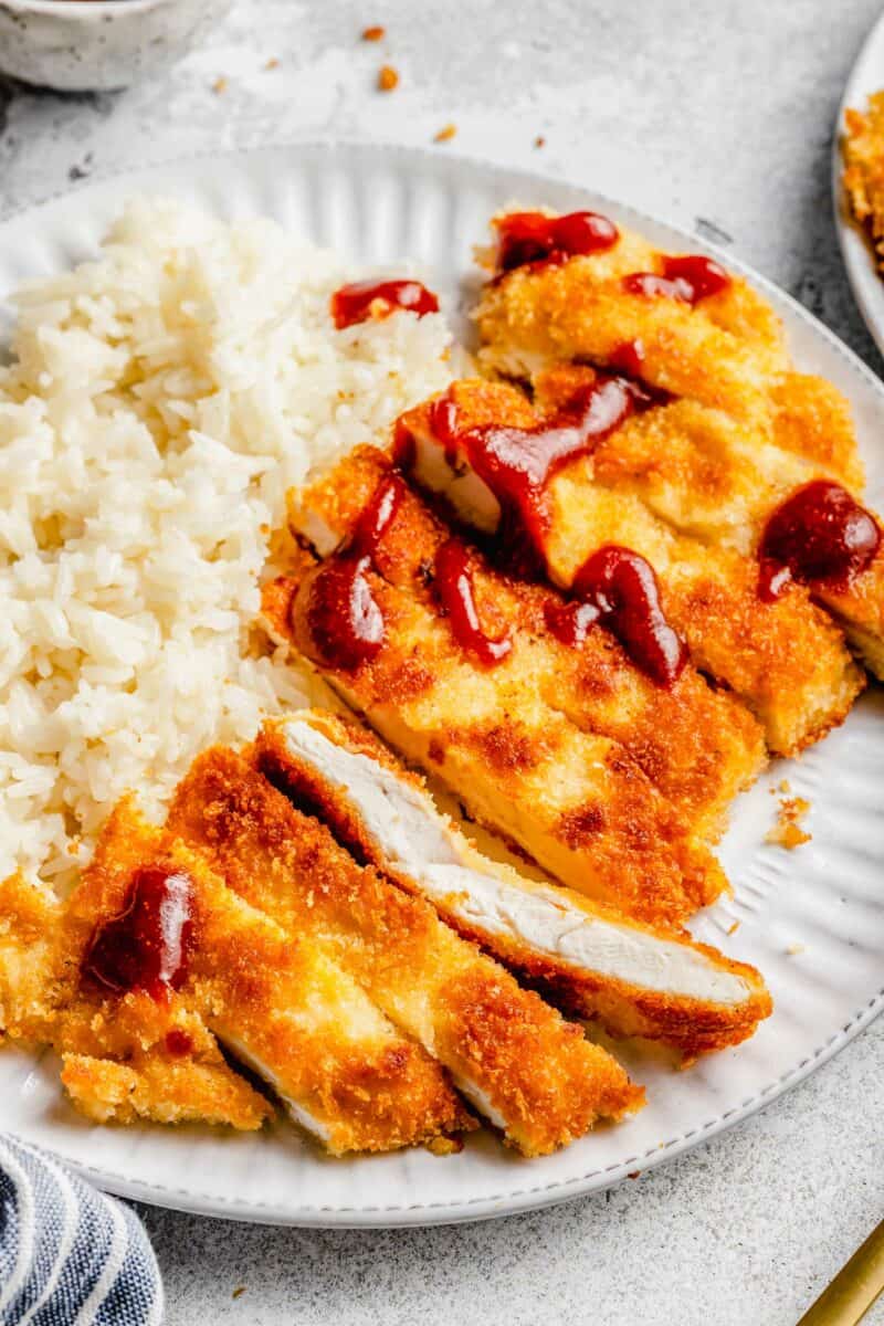Red sauce is drizzled over katsu chicken. 