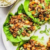Chicken lettuce wraps garnished with green onions.