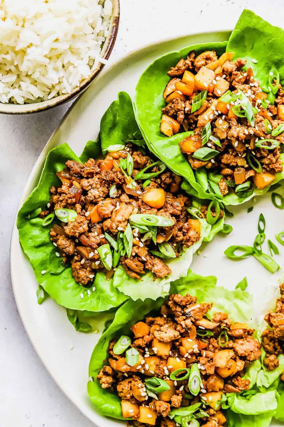 Chicken lettuce wraps garnished with green onions.
