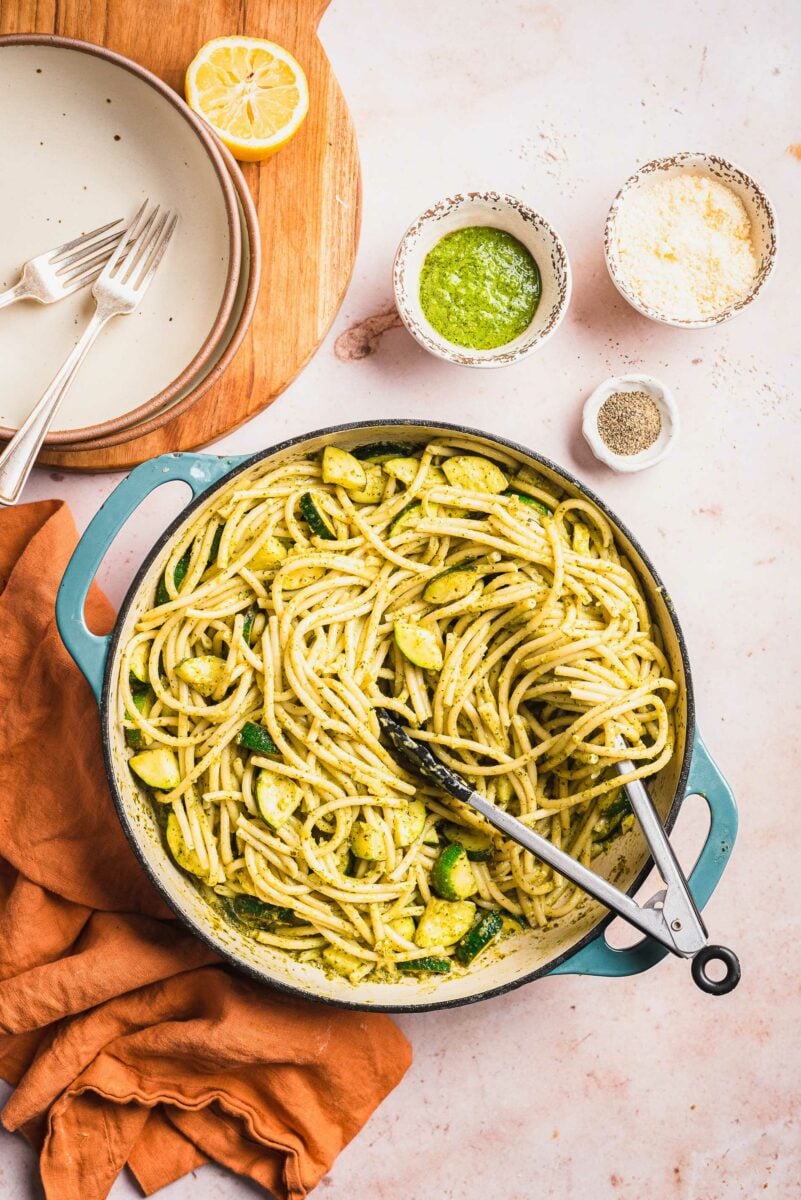 Tongs are placed in a large pot filled with creamy lemon zucchini pasta. 