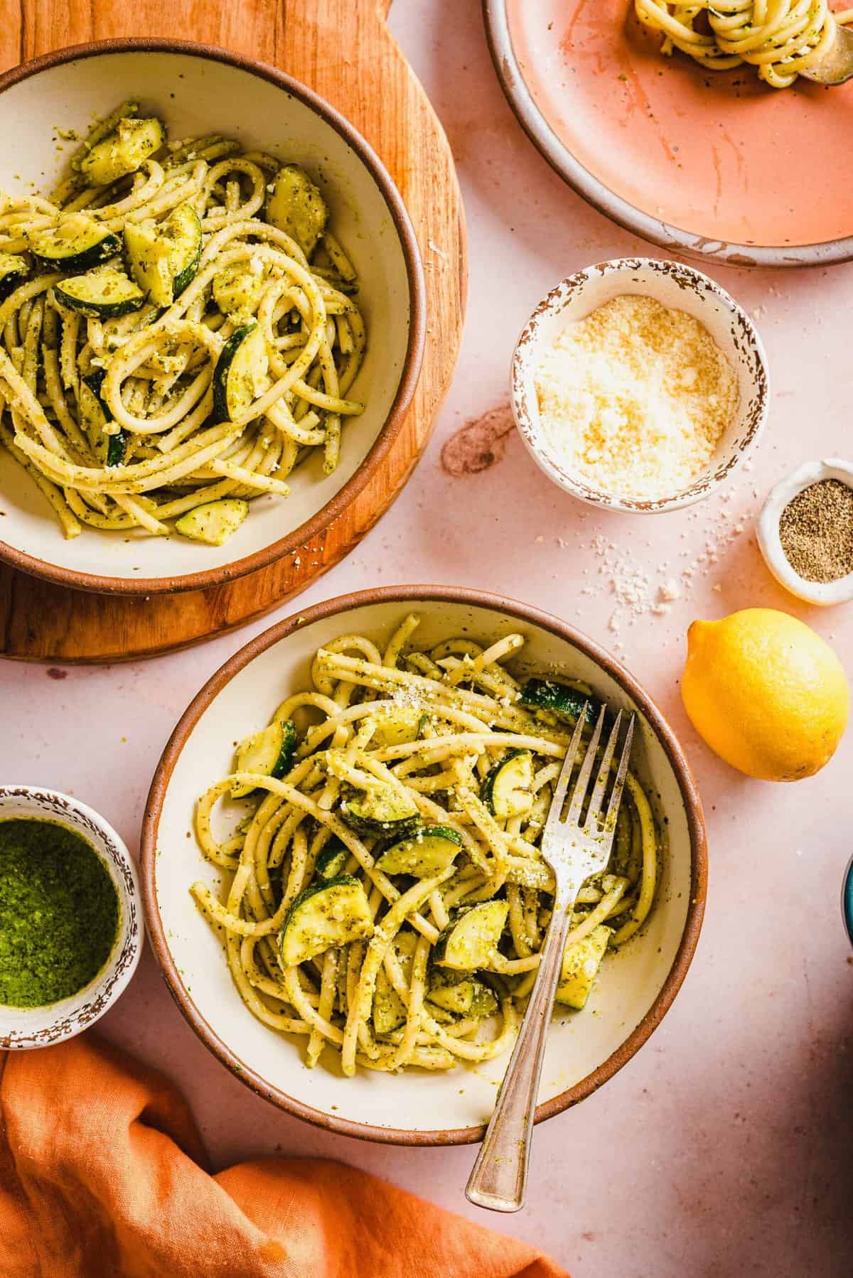 A small white bowl is filled with pasta and presented with a fork. 