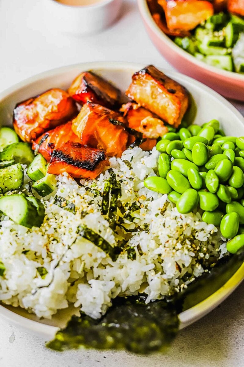 A salmon rice bowl is served in a white bowl. 