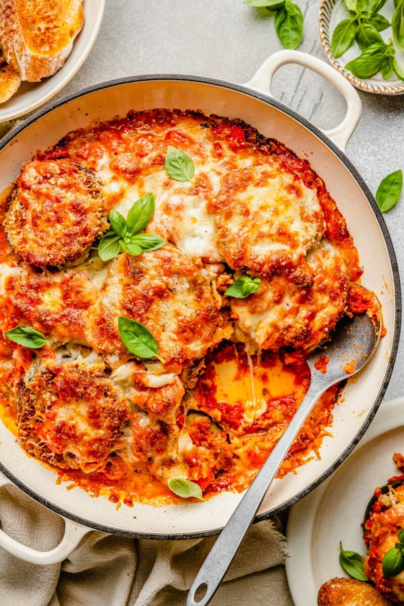 overhead shot of eggplant parmesan in round baking dish with one slice taken out