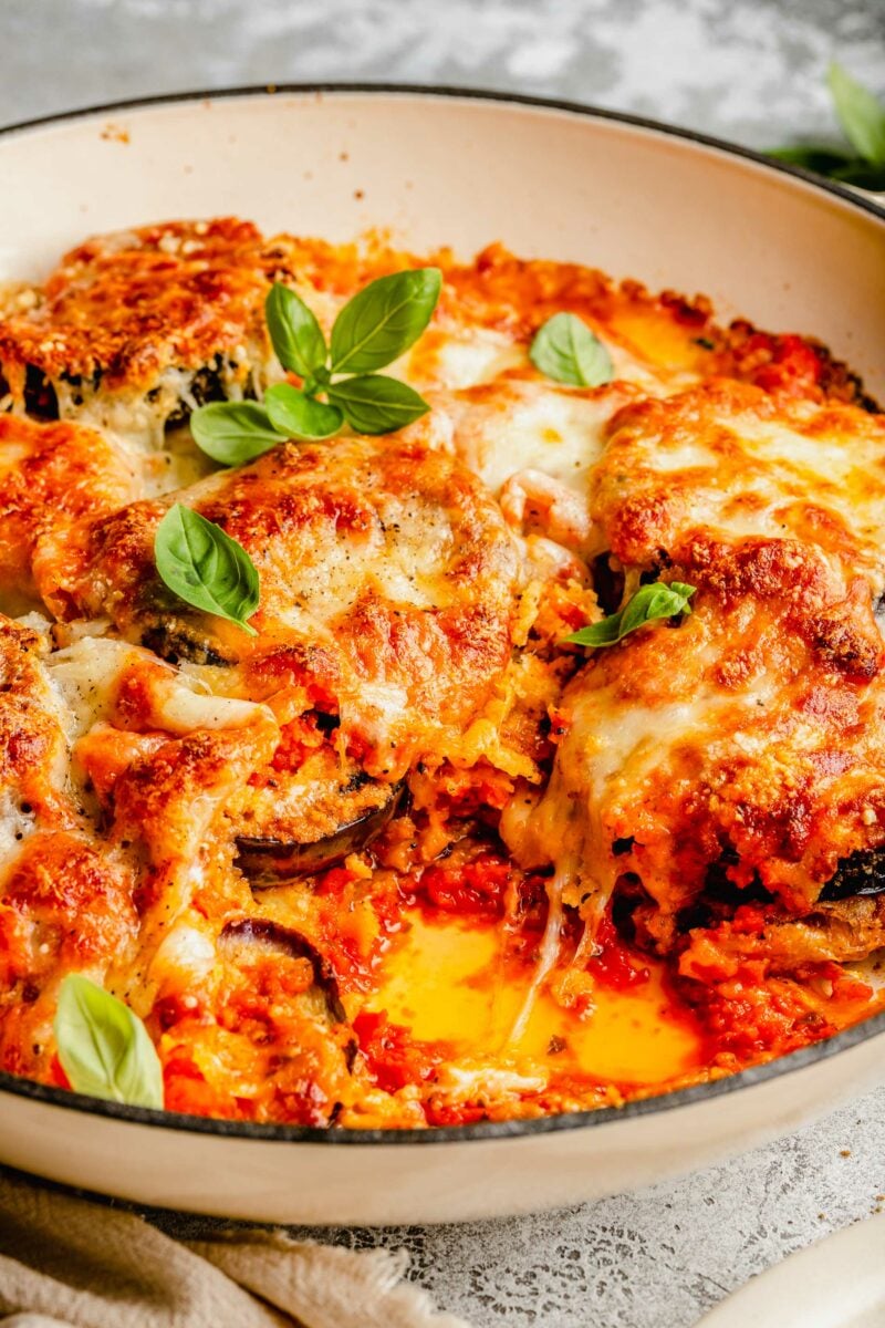 close up of eggplant parmesan in round baking dish where you can see the tomato sauce and gooey cheese