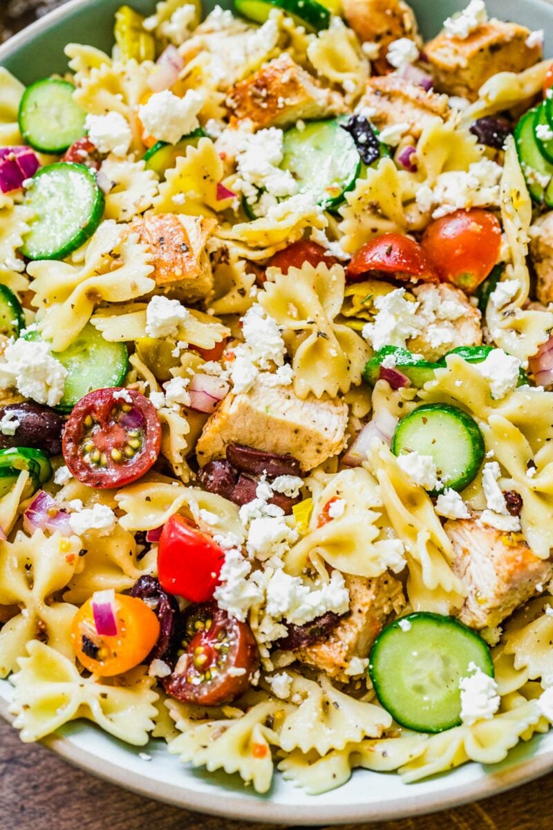 A close up shot reveals all of the pasta salad ingredients tossed together. 