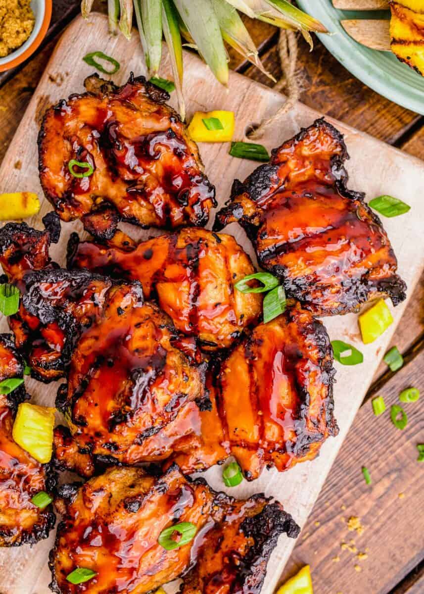 Glazed chicken thighs are topped with pineapple and green onions. 