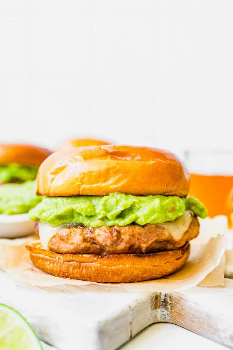 A grilled patty, cheese, and avocado are sandwiched between two buns.
