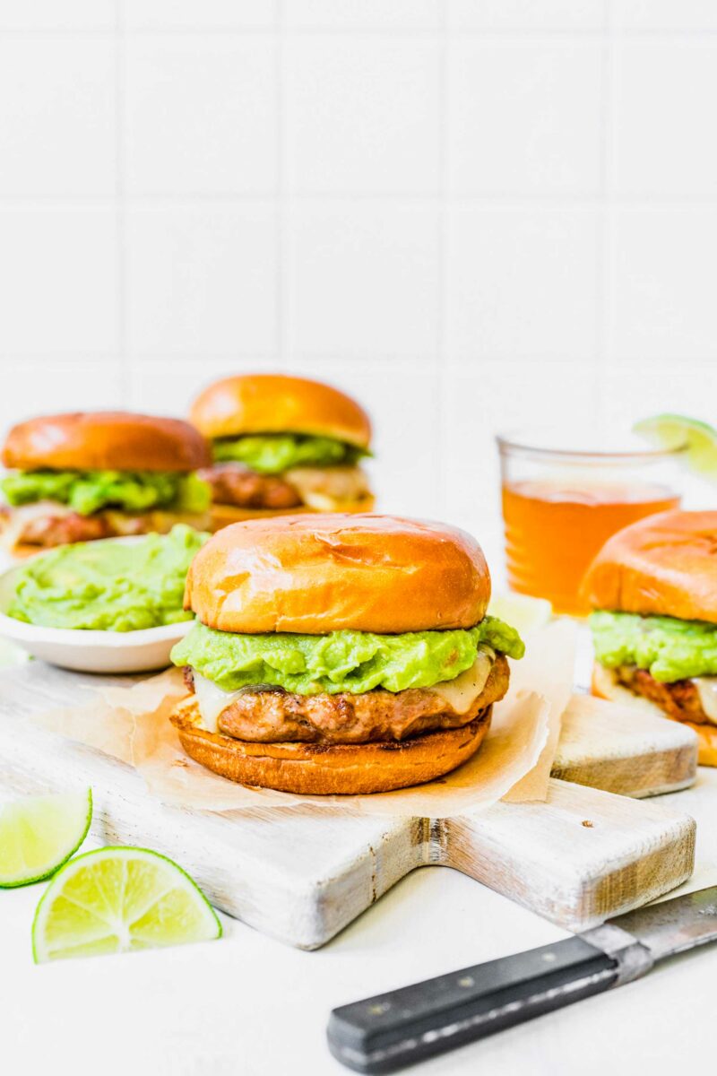 Several turkey chorizo  burgers are placed on a table with lime slices. 