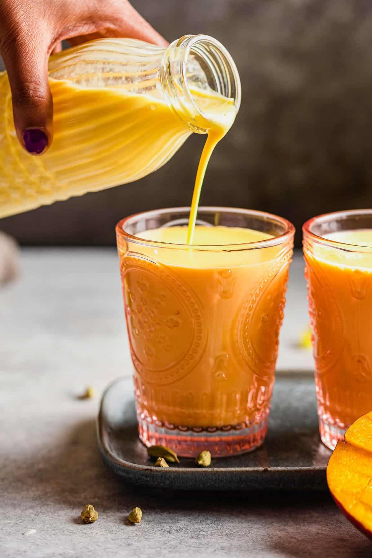 Pouring mango lassi into a glass
