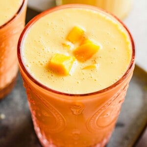 Overhead view of mango lassi in glass, garnished with cubes of mango