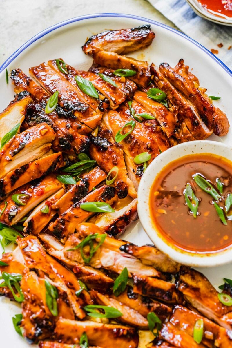 Chopped scallions are sprinkled across the top of grilled sliced grilled thighs. 