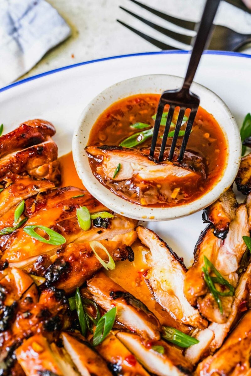 A piece of chicken is being dunked into more glaze. 