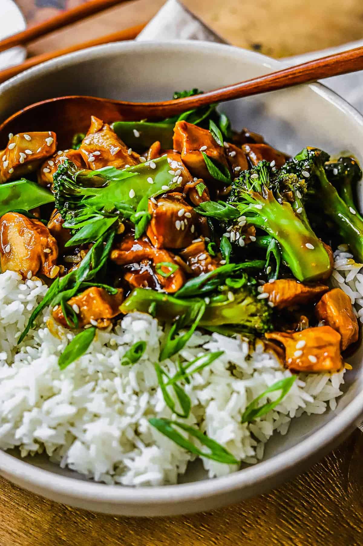 close up of white bowl filled with rice and teriyaki chicken and broccoli