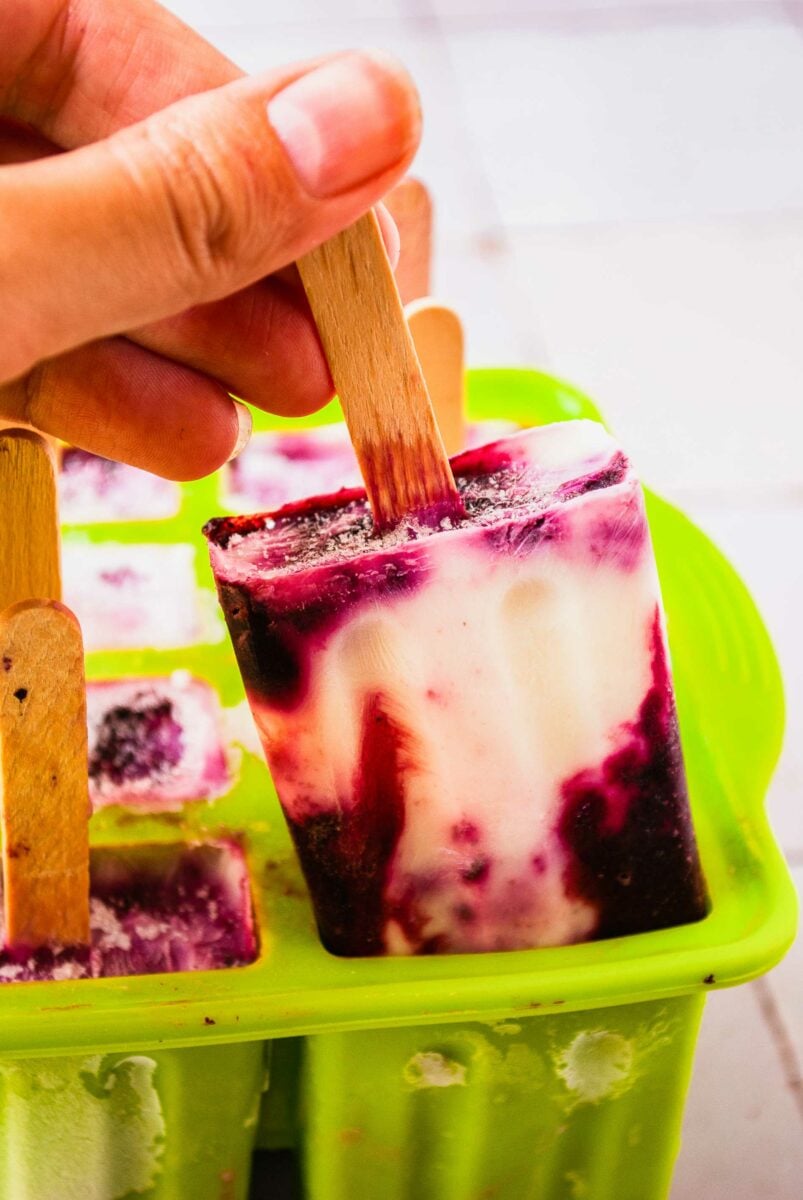 A popsicle is being removed from a vibrant green mold. 