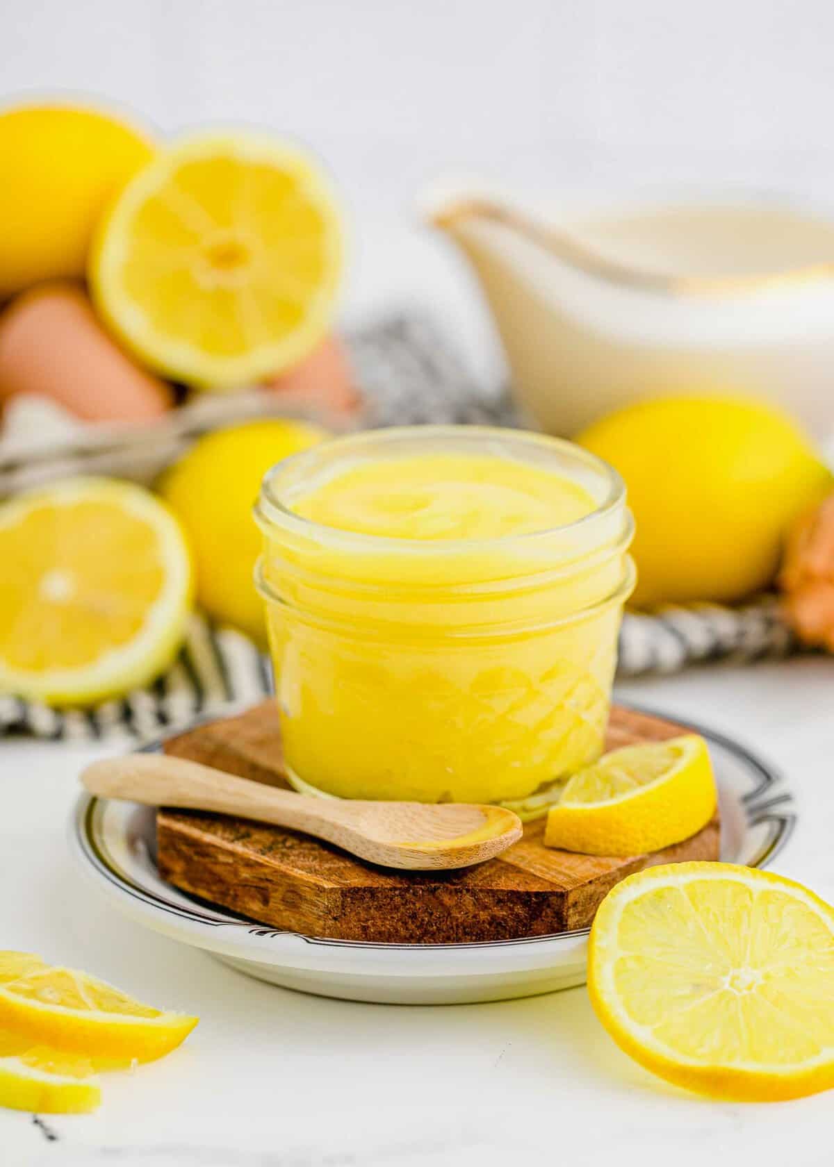 Jar of lemon curd with spoon and lemons in background